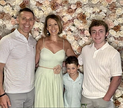 Geoffrey Abrams posing with his family in front of a floral wall
