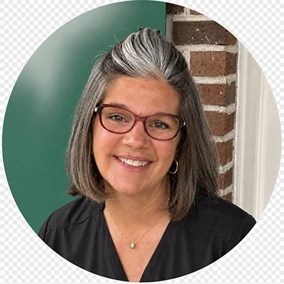 Robin smiling while wearing black scrubs and glasses